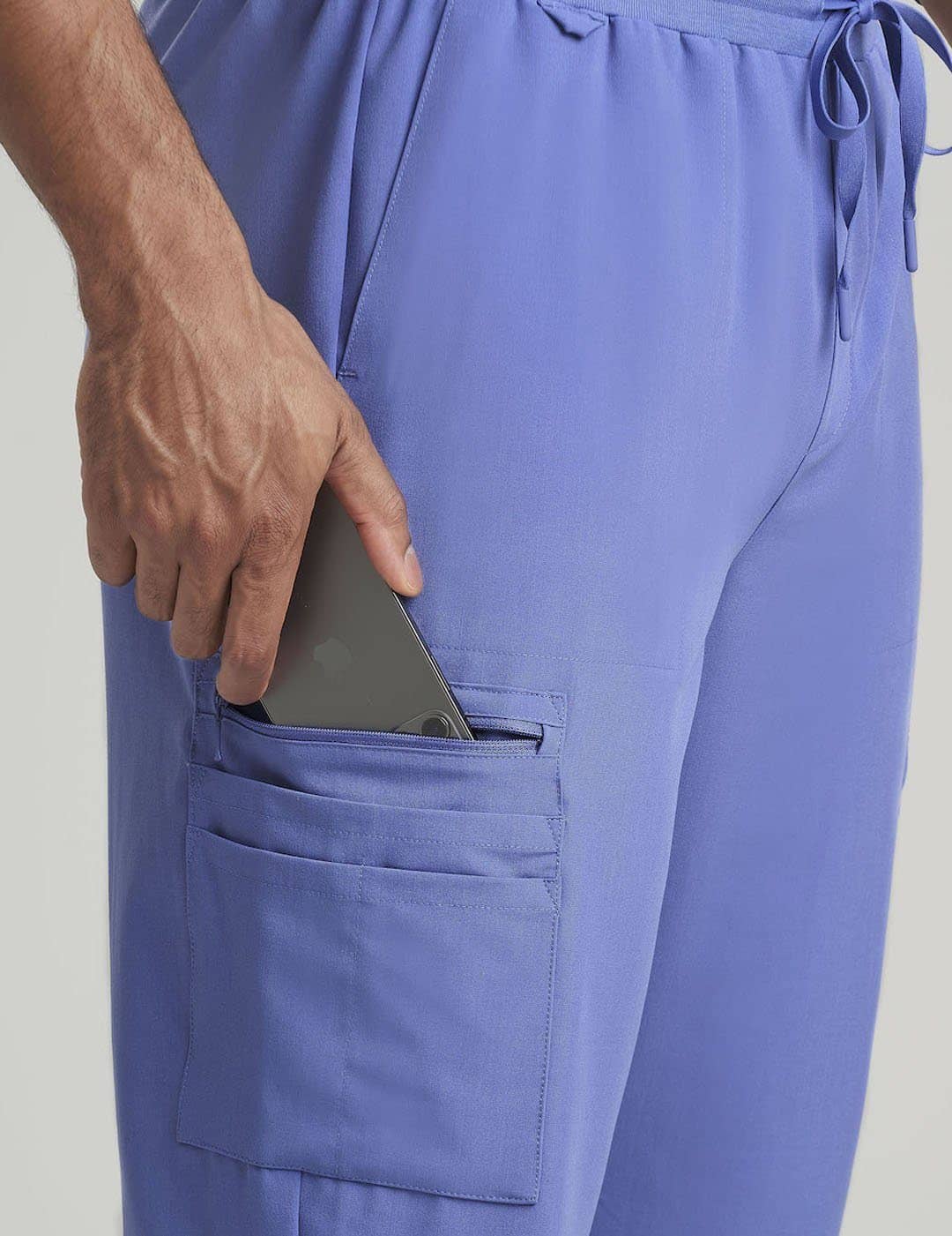 Ceil Men's 10-Pocket Jogger Scrub Pants by Care+Wear, featuring a light color and functional design for a relaxed yet professional look. Model is wearing size Large