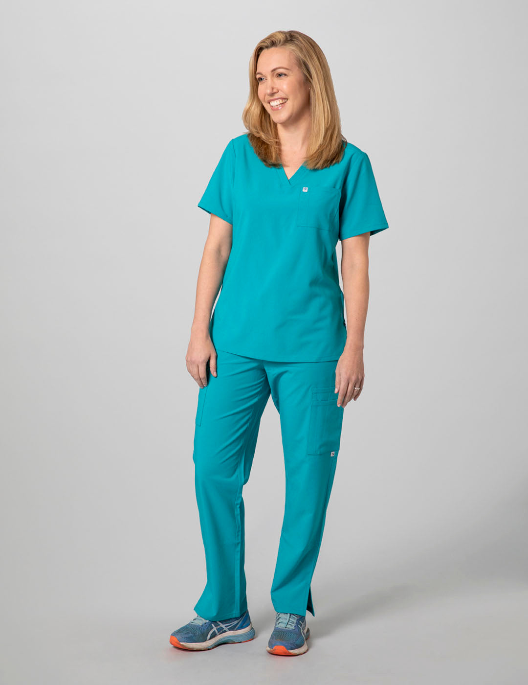 Care+Wear Women's 2-Pocket V-Neck Scrub Top in Teal, combining a calming hue with functional design for medical professionals. Model is wearing size Small