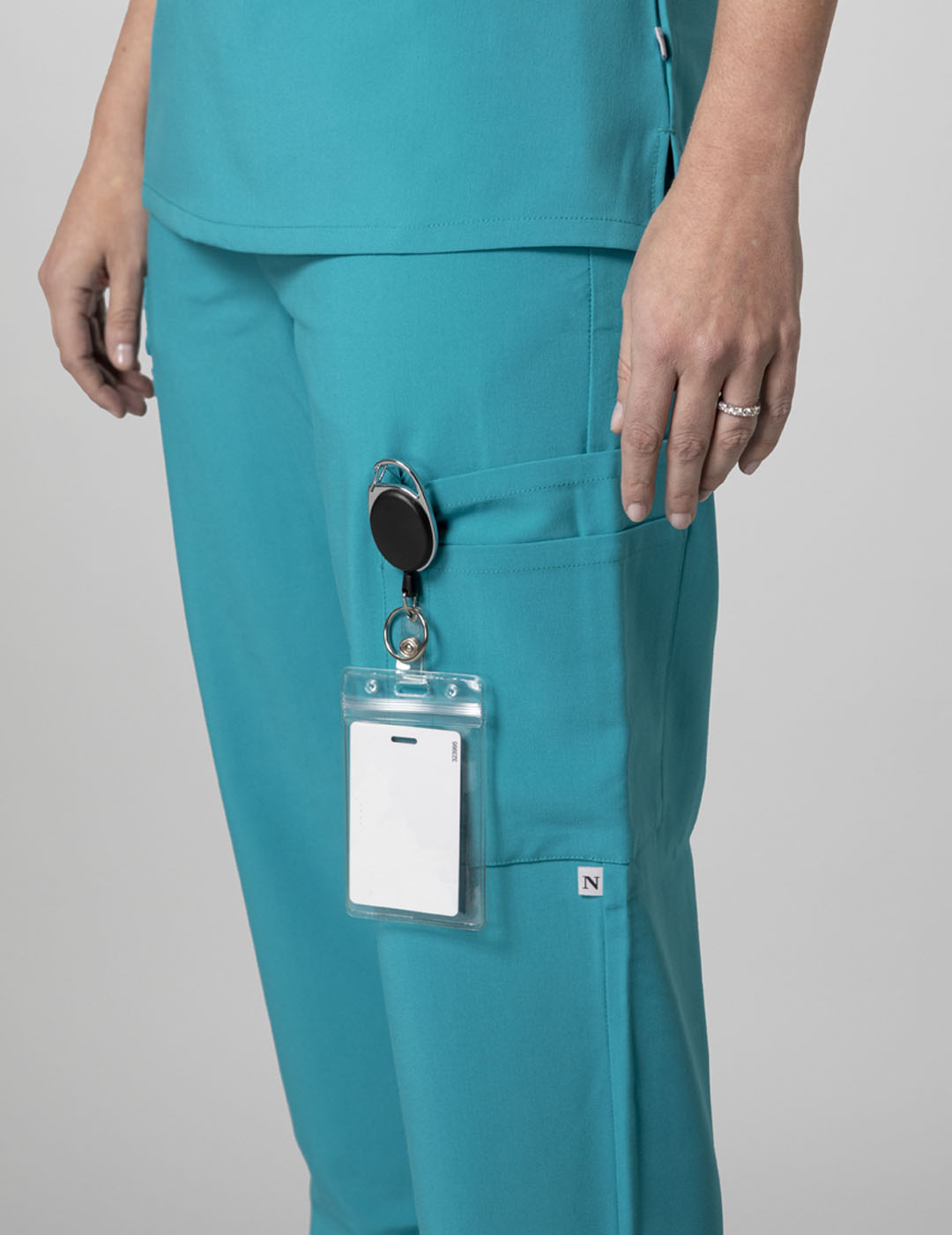 Teal women's straight-leg scrub pants with nine pockets, offering style and utility