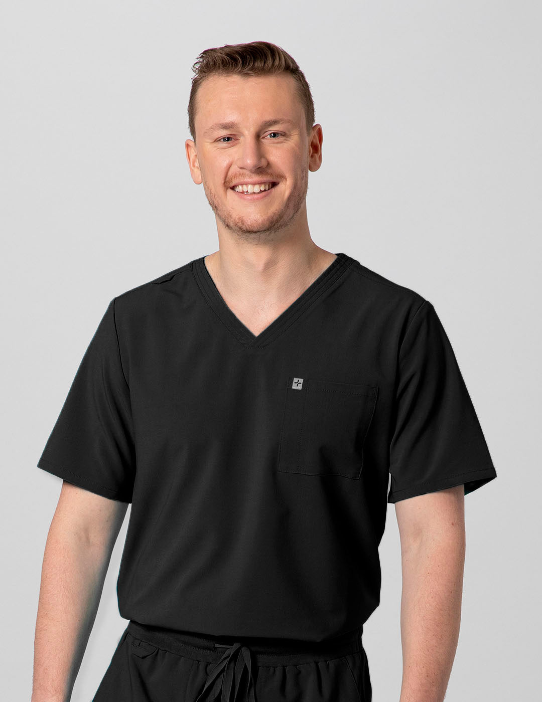 Men's 2-pocket V-neck scrub top in black, offering a sleek and professional design for healthcare settings. Model is wearing size Medium