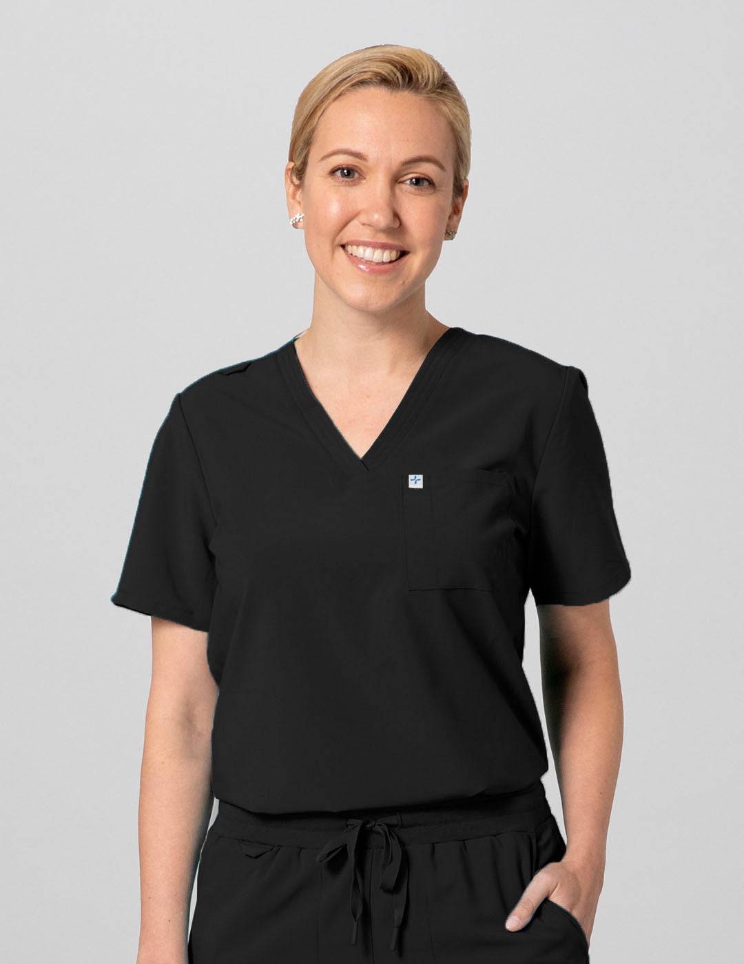 Classic Black Women's 2-Pocket V-Neck Scrub Top by Care+Wear, designed for durability, comfort, and essential storage. Model is wearing size Small