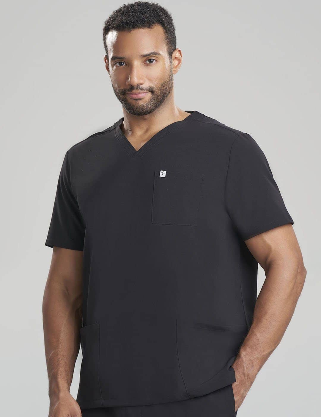 Care+Wear Men's 3-Pocket V-Neck Scrub Top in Black, featuring a minimalist design with essential pockets for healthcare settings. Model is wearing size Large