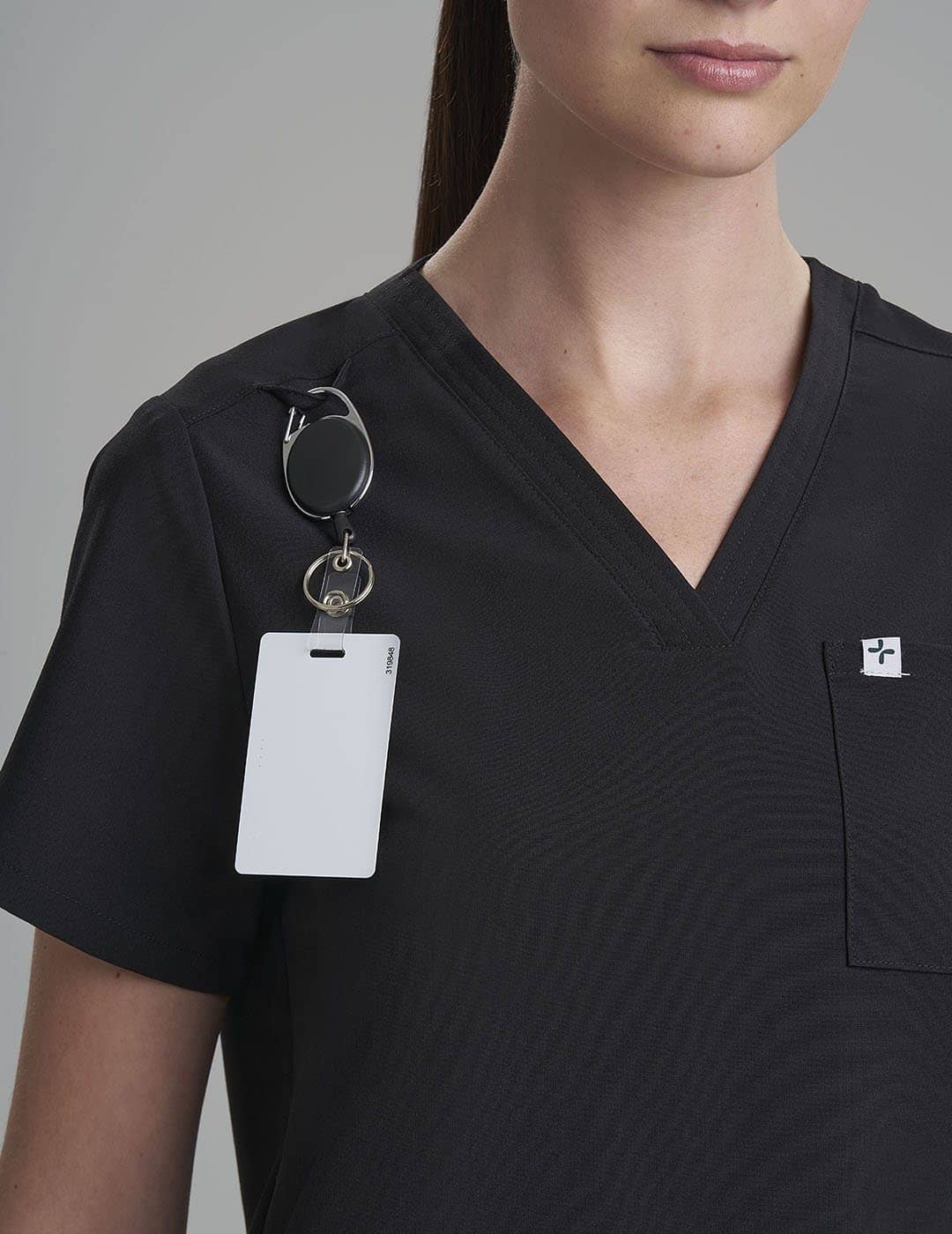 Care+Wear Women's 3-Pocket V-Neck Scrub Top in Black, combining sleek style with practical storage solutions for healthcare providers. Model is wearing size X-Small