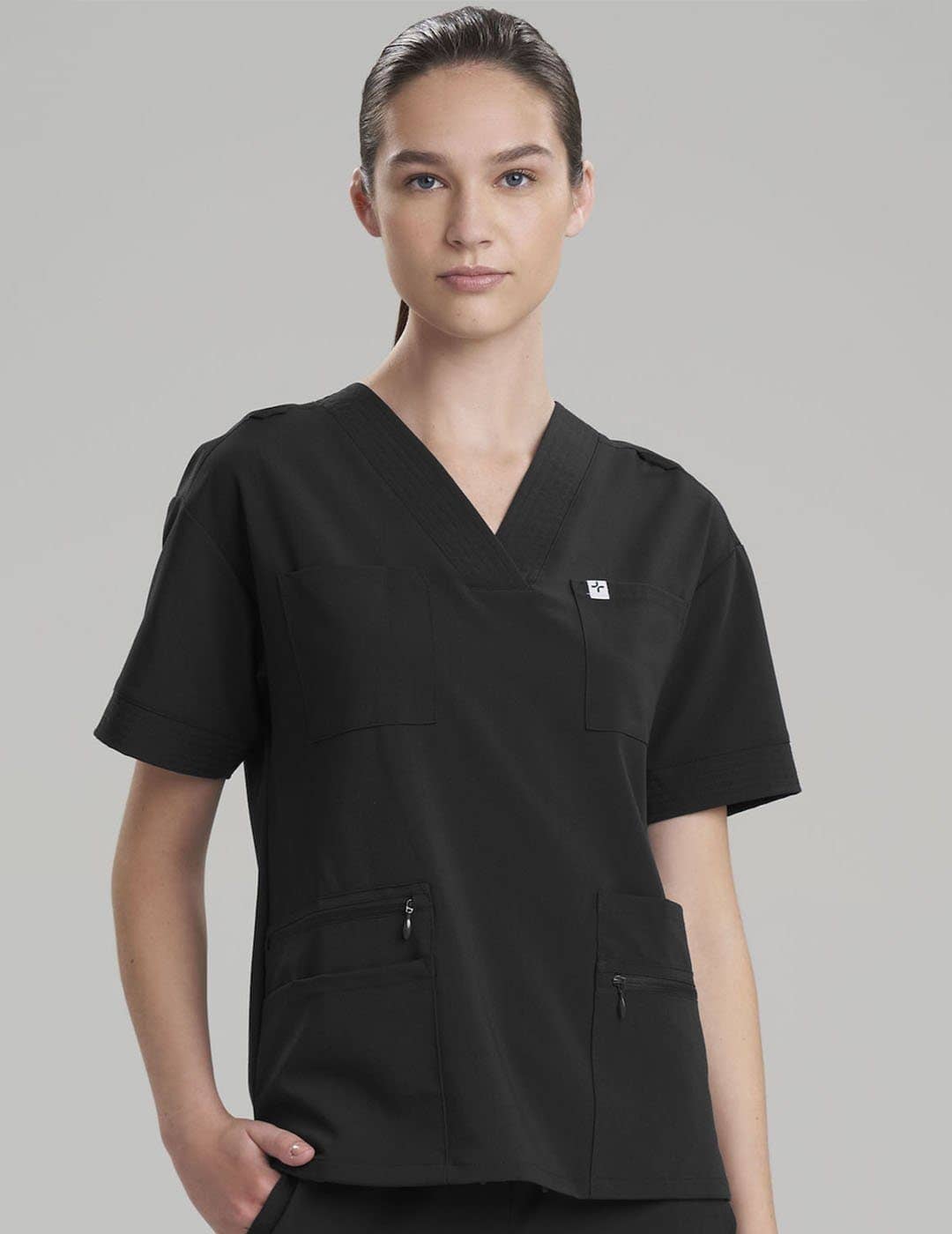 Functional women's scrub top in ceil, designed for comfort and equipped with eight pockets. Model is wearing size X-Small