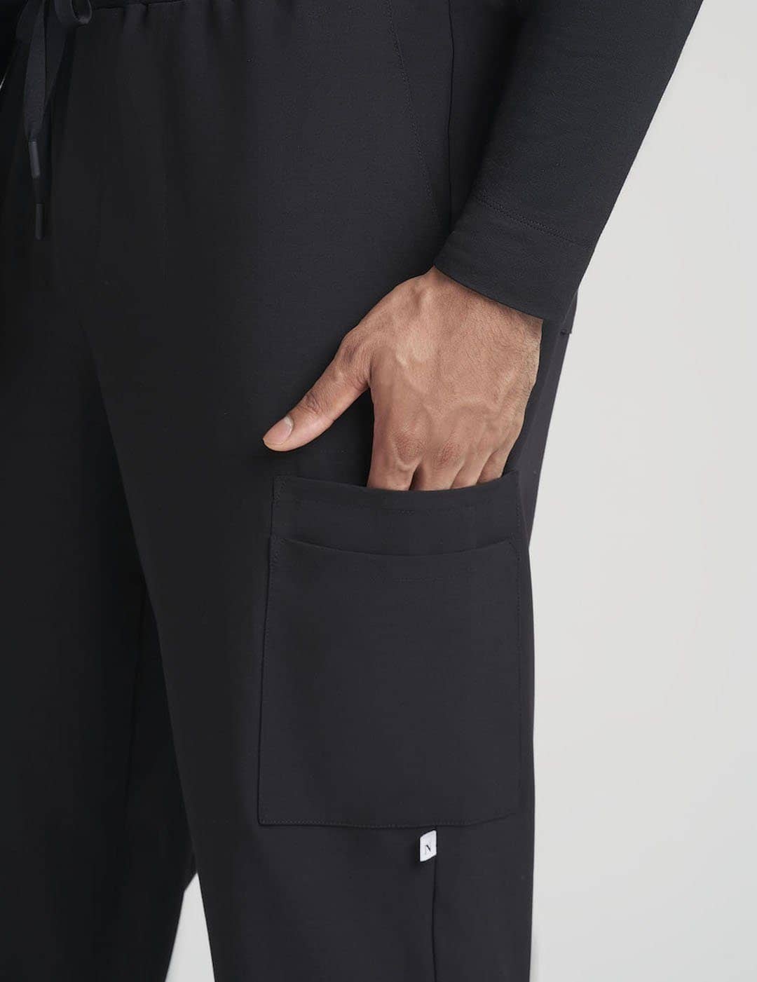 Classic Black Men's 10-Pocket Jogger Scrub Pants from Care+Wear, designed for durability, style, and abundant storage options. Model is wearing size Large