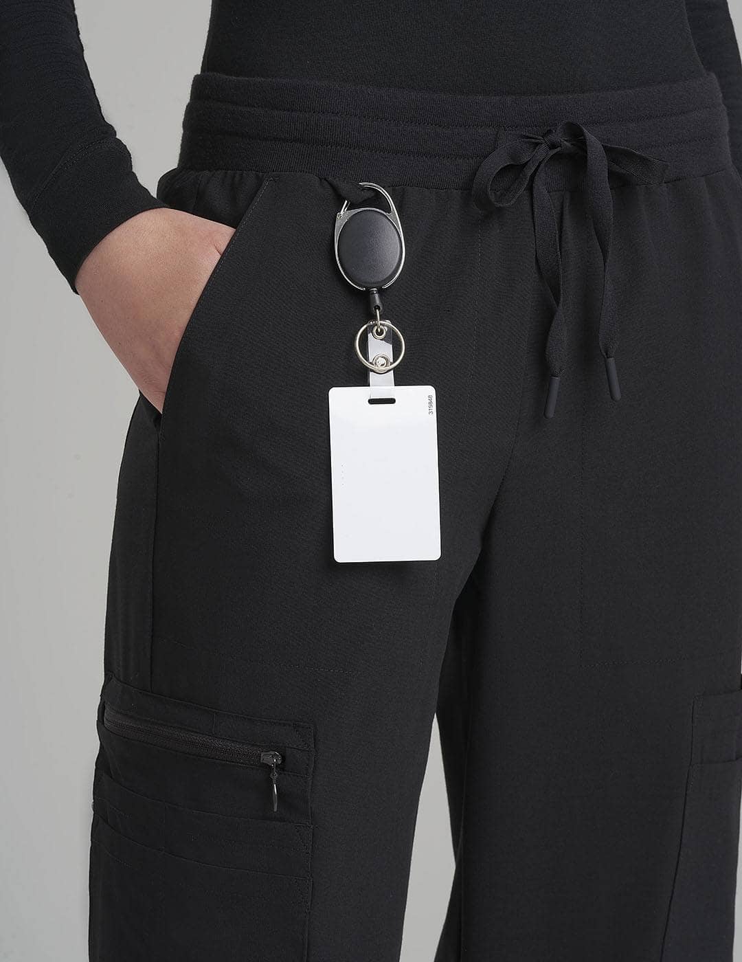 Classic Black Women's 12-Pocket Scrub Jogger Pants from Care+Wear, offering extensive storage and a sleek professional look. Model is wearing size X-Small