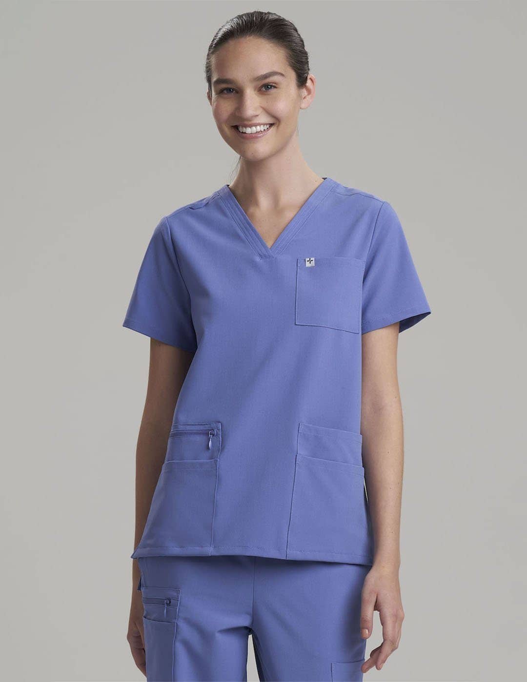 Durable royal blue V-neck scrub top for women, crafted with six pockets for everyday use. Model is wearing size X-Small