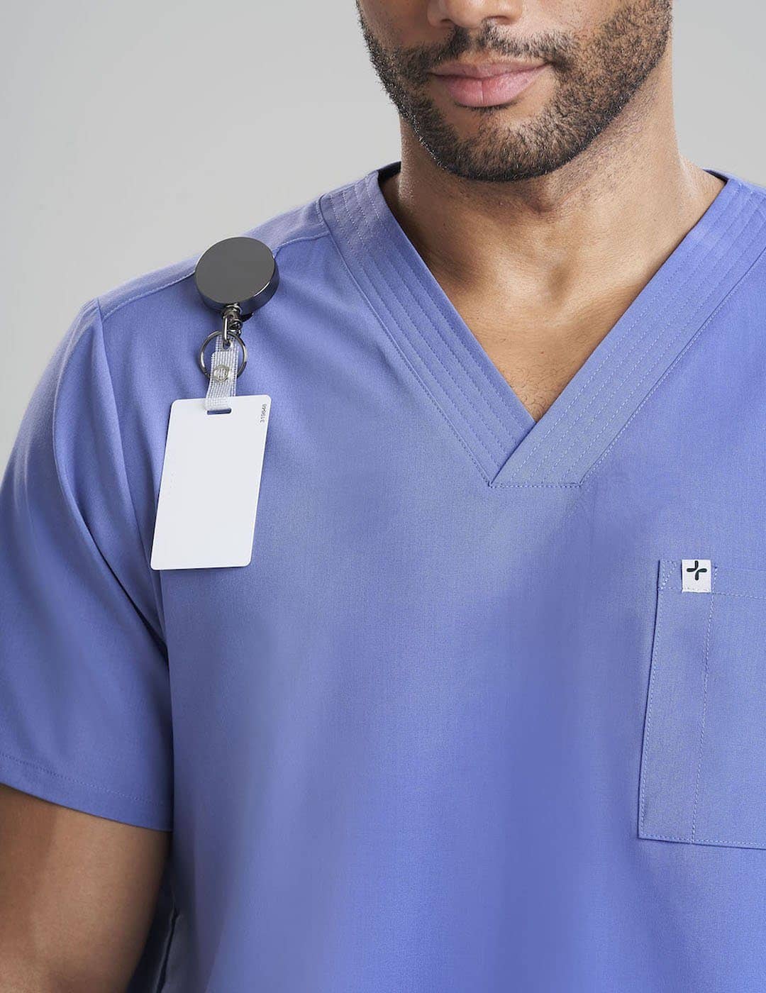 Care+Wear Men's 7-Pocket V-Neck Scrub Top in Ceil, offering a light, breathable fabric with ample storage for medical tools. Model is wearing size Large