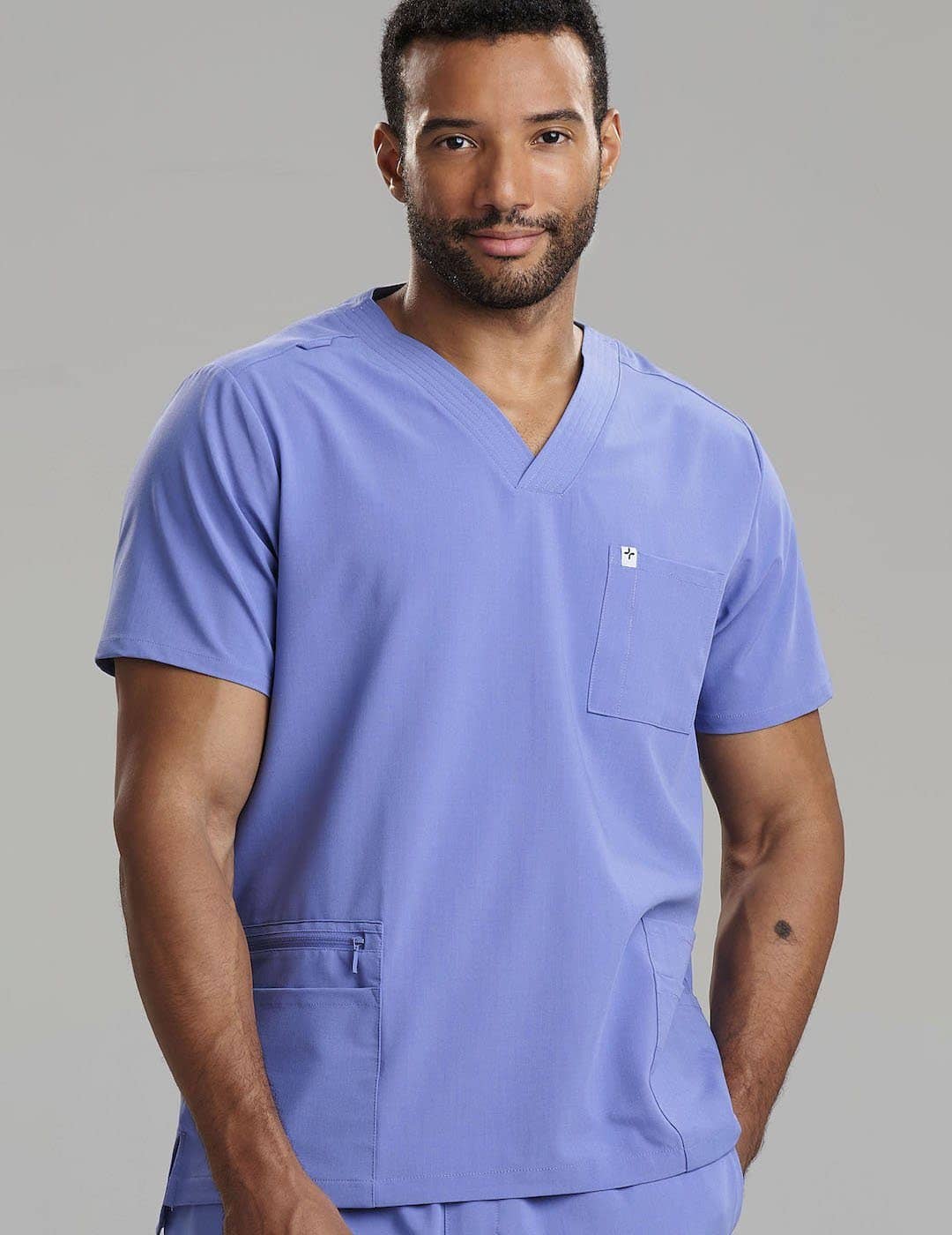 Care+Wear Men's 7-Pocket V-Neck Scrub Top in Ceil, offering a light, breathable fabric with ample storage for medical tools. Model is wearing size Large