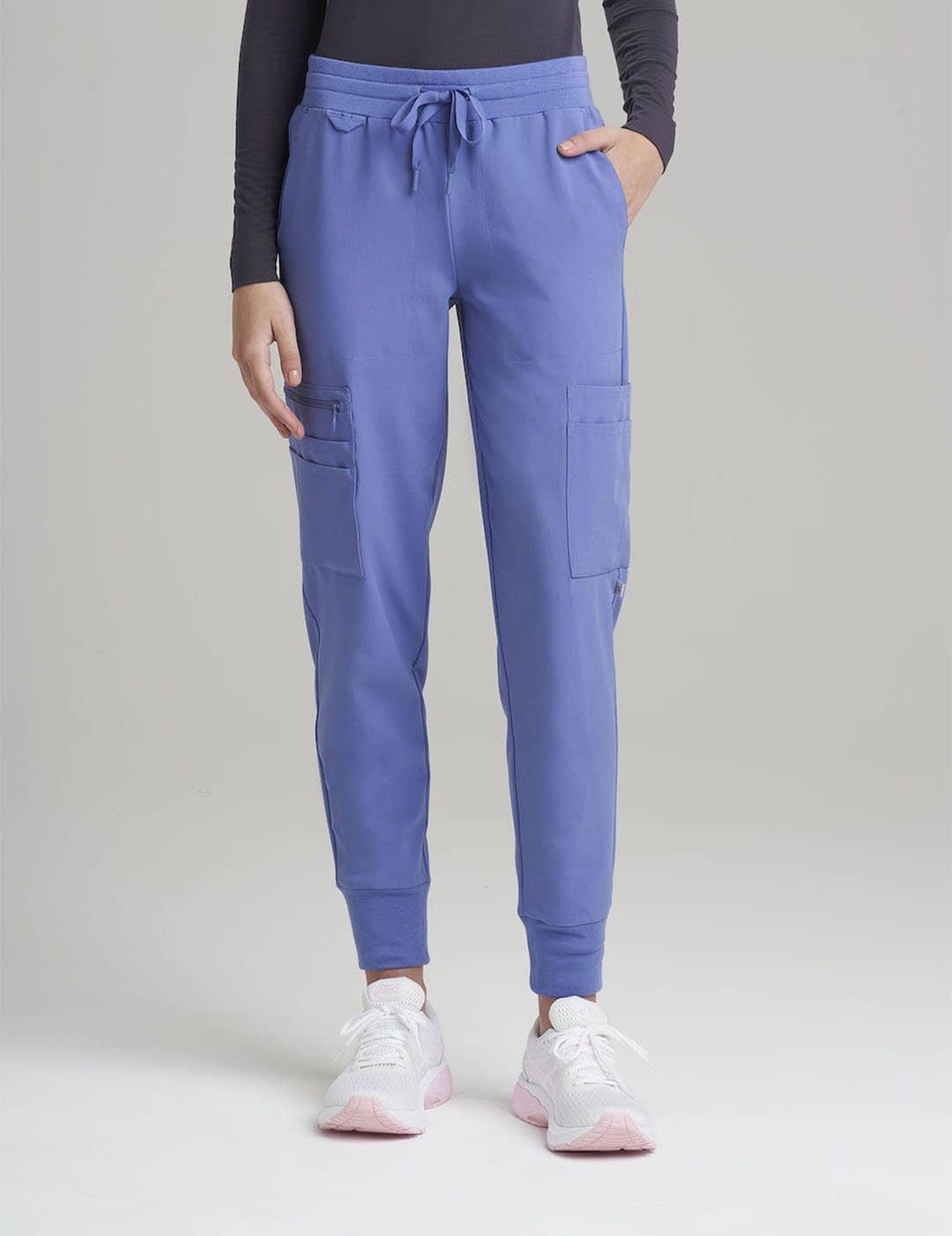 Care+Wear Women's 12-Pocket Scrub Jogger Pants in Ceil, offering bright, functional workwear with plenty of pockets for essentials. Model is wearing size X-Small