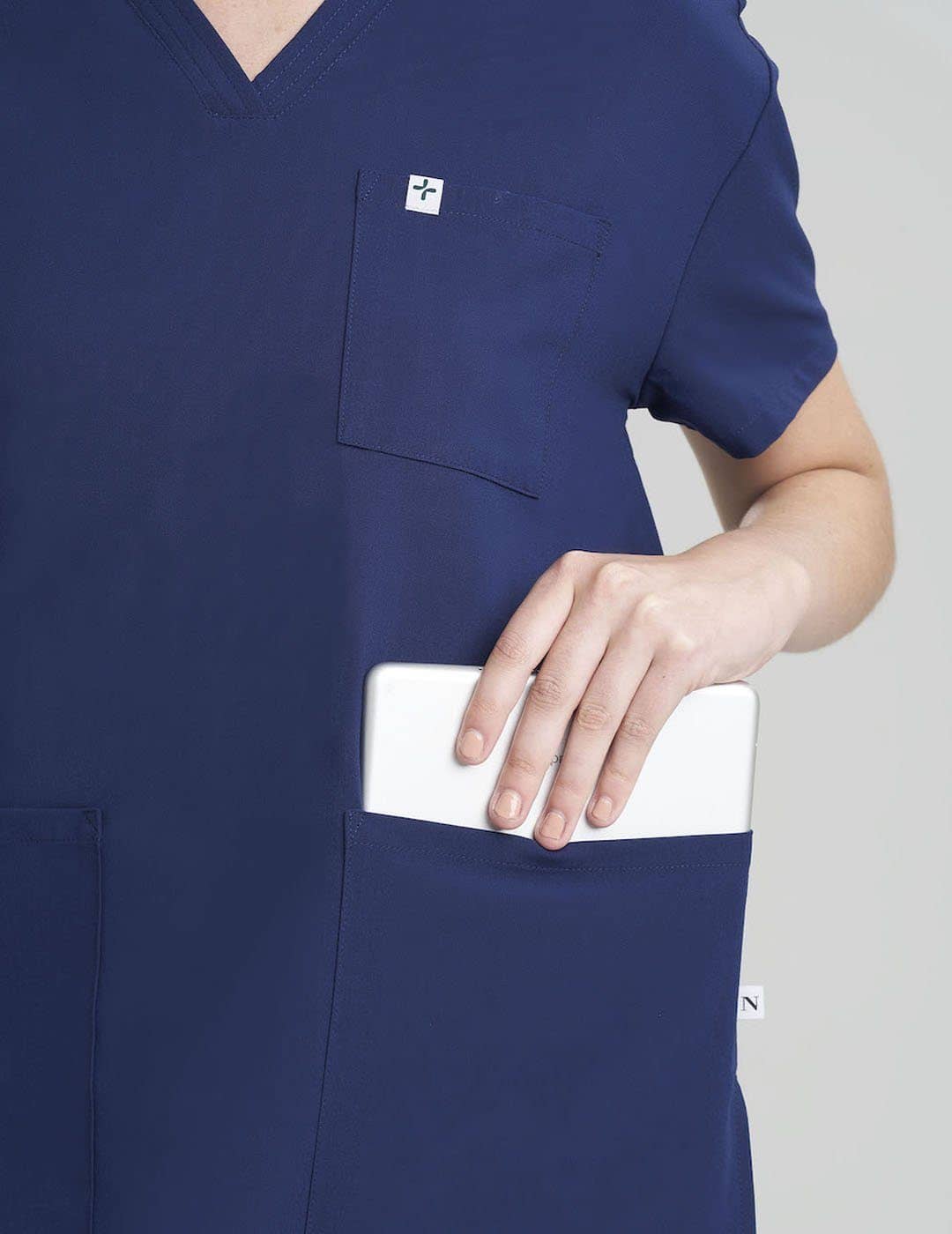 Care+Wear Women's 3-Pocket V-Neck Scrub Top in Navy, offering stylish design with ample pocket storage for healthcare work. Model is wearing size X-Small