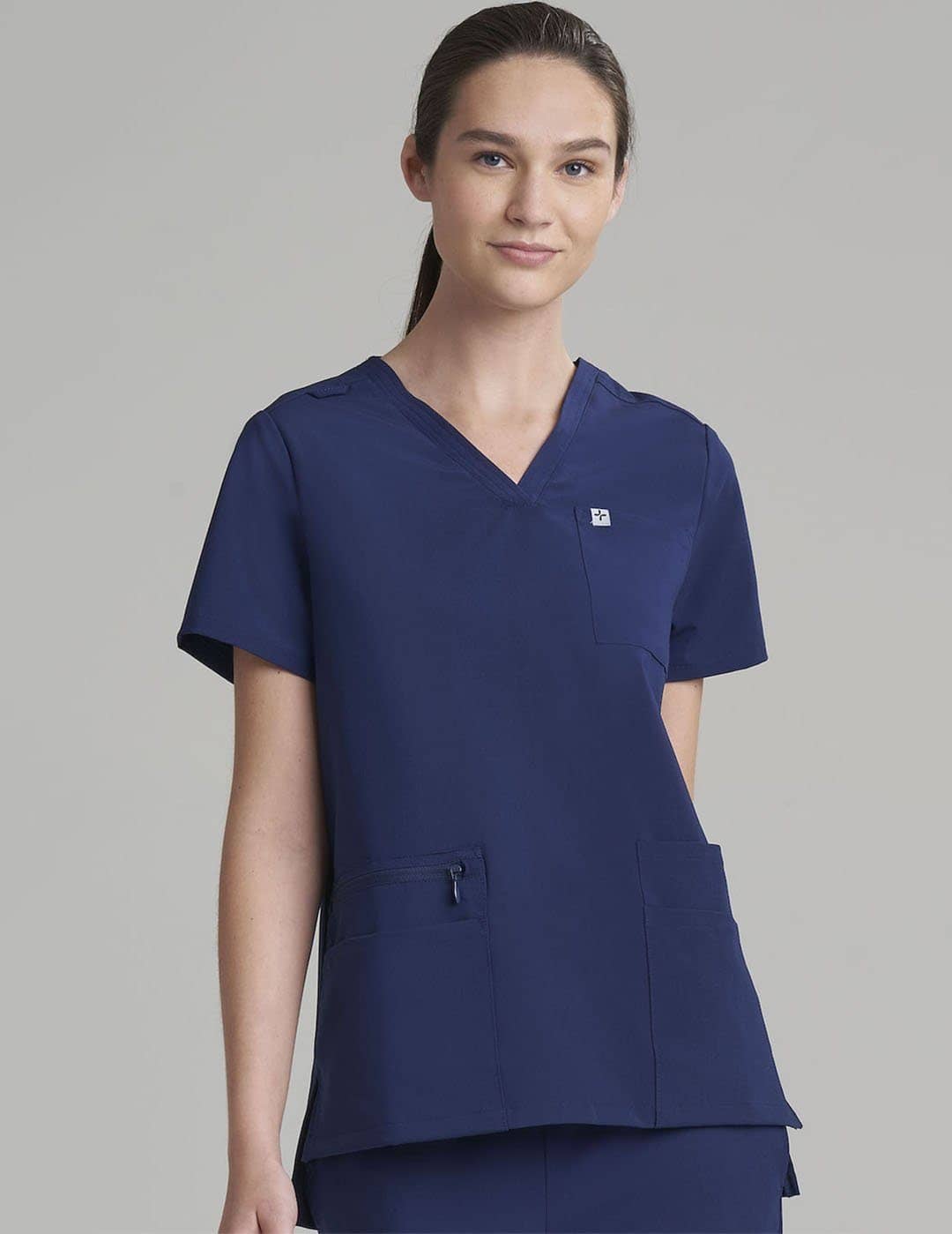 Durable royal blue V-neck scrub top for women, crafted with six pockets for everyday use. Model is wearing size X-Small