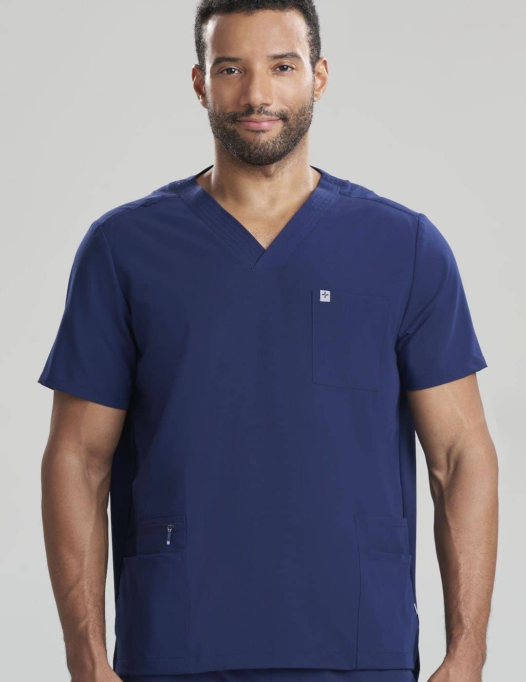 Care+Wear Men's 7-Pocket V-Neck Scrub Top in Navy, offering ample storage and a professional look for healthcare providers. Model is wearing size Large