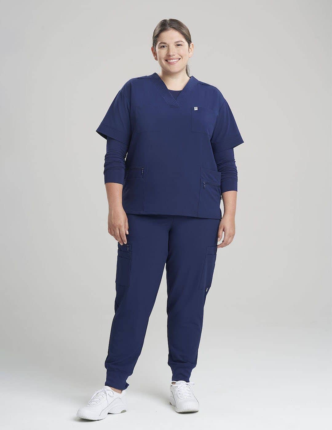 Stylish women's scrub top in royal blue, combining a sleek V-neck design with ample storage. Model is wearing size Large