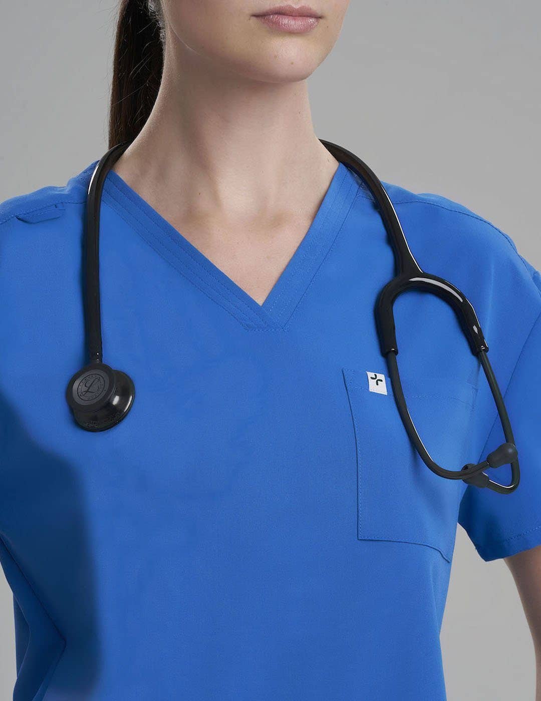Royal Blue Women's 3-Pocket V-Neck Scrub Top from Care+Wear, blending a vibrant hue with functional pocket design for healthcare professionals. Model is wearing size X-Small
