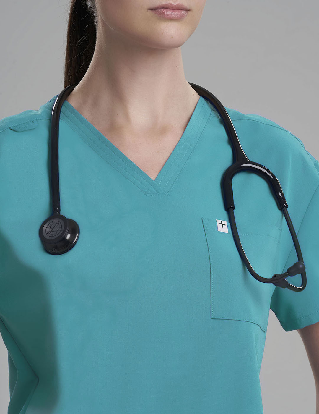Teal women's V-neck scrub top with three pockets, combining functionality with a vibrant look