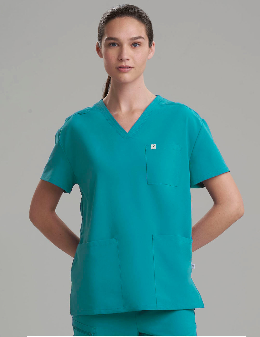 Teal women's V-neck scrub top with three pockets, combining functionality with a vibrant look