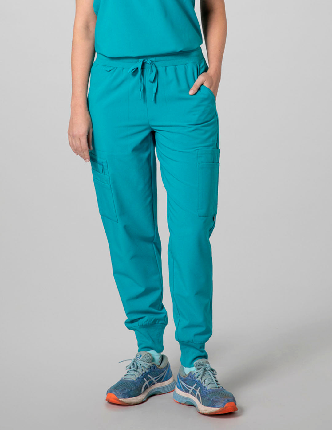 Care+Wear Women's 12-Pocket Scrub Jogger Pants in Teal, combining practicality with a vibrant color for comfort in clinical settings. Model is wearing size Small