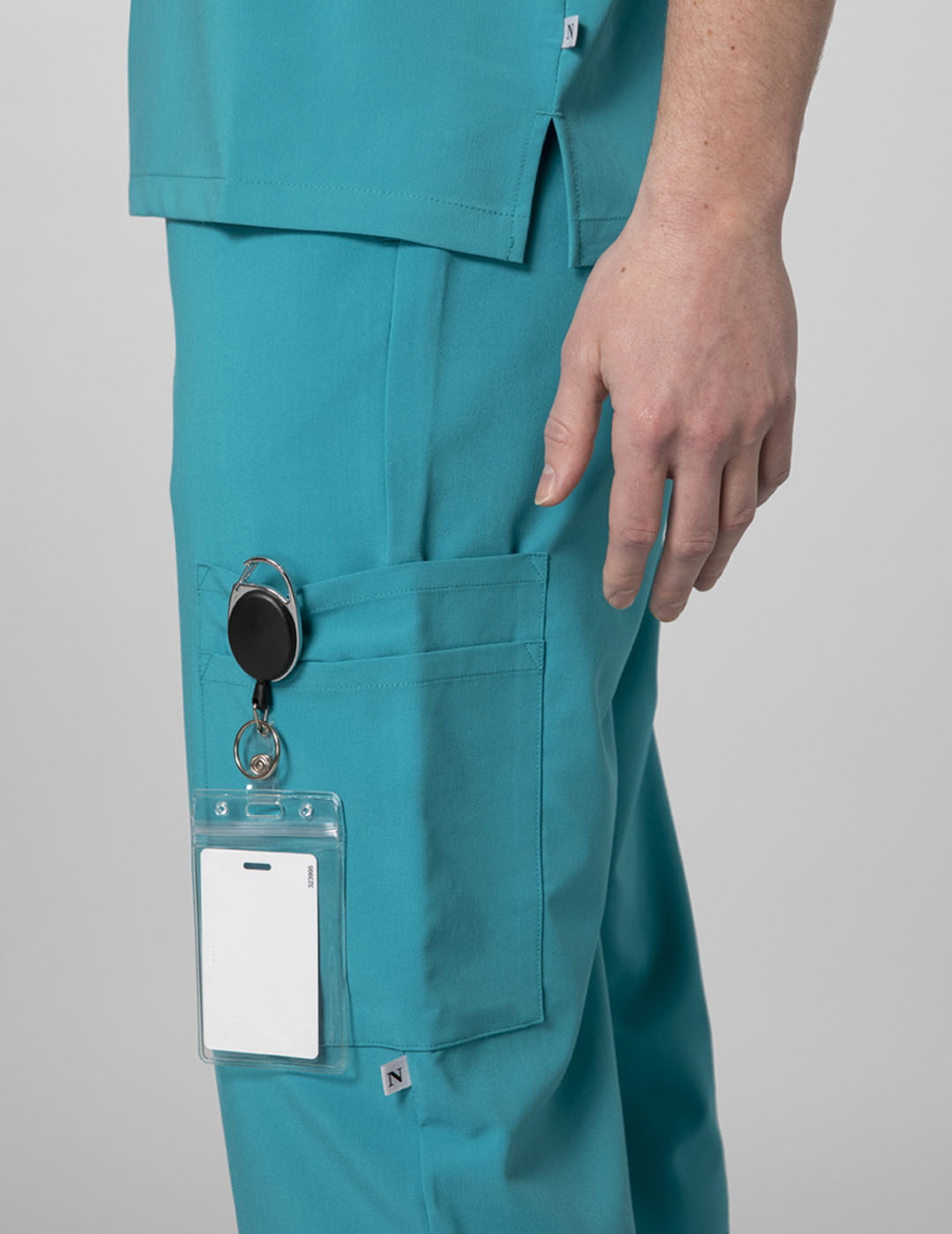 Care+Wear Men's 7-Pocket Straight Leg Scrub Pants in Teal, offering practical design and ample storage for healthcare tasks. Model is wearing size Medium