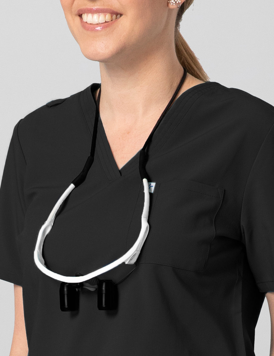 Classic Black Women's 2-Pocket V-Neck Scrub Top by Care+Wear, designed for durability, comfort, and essential storage. Model is wearing size Small