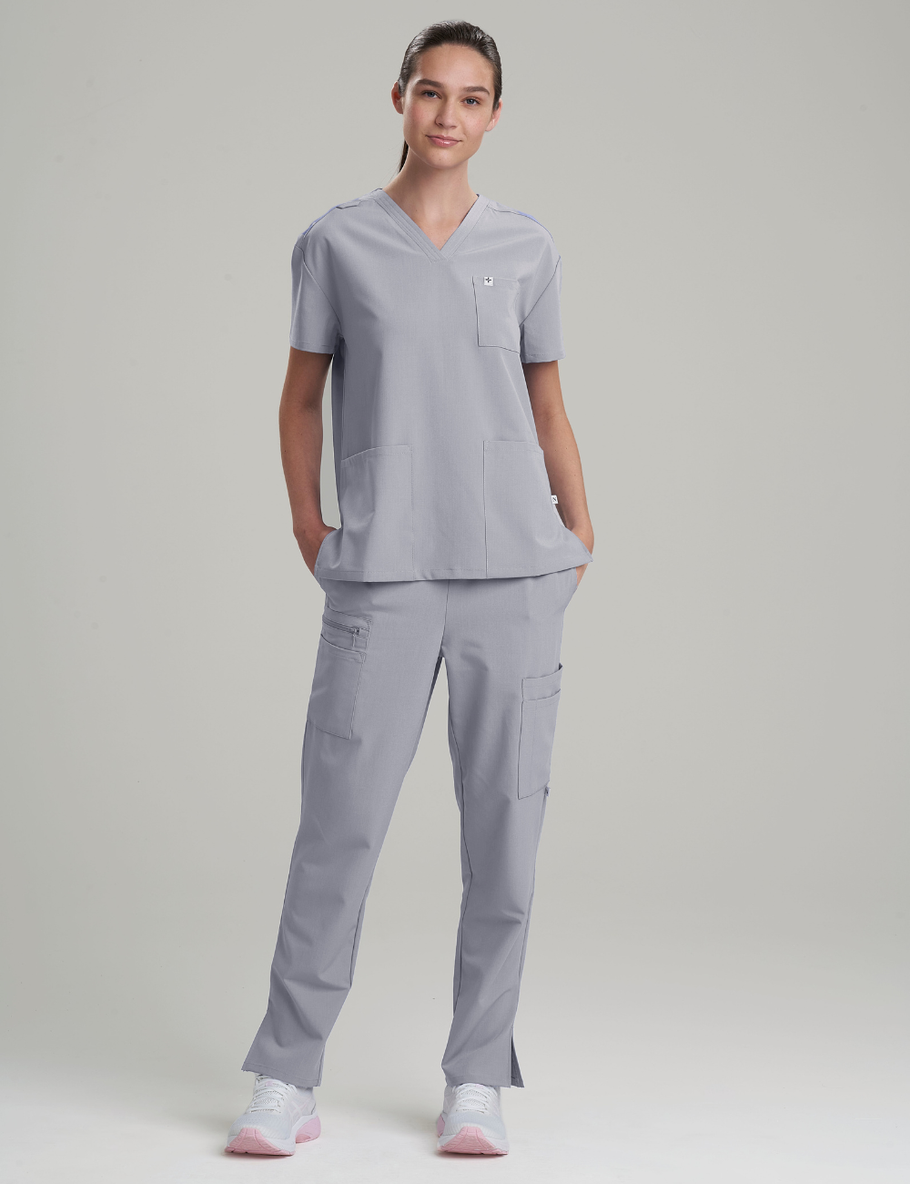 Women&#39;s V-neck scrub top in stone gray, designed for comfort and functionality with three spacious pockets.