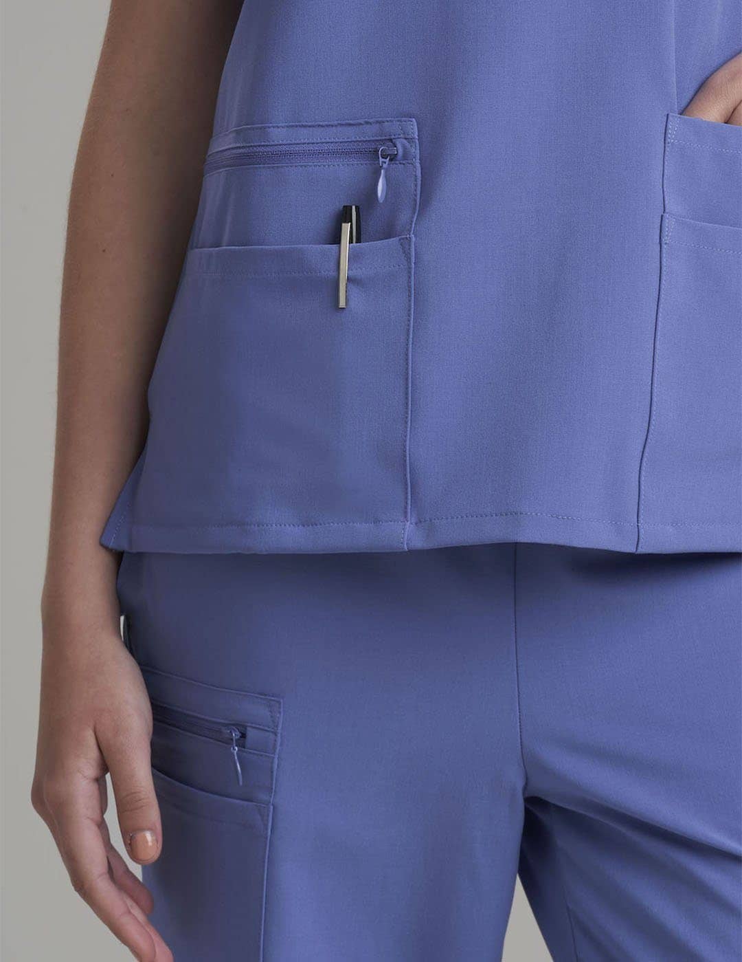 Women's 6-pocket V-neck scrub top in ceil, offering a modern design and practical storage. Model is wearing size X-Small