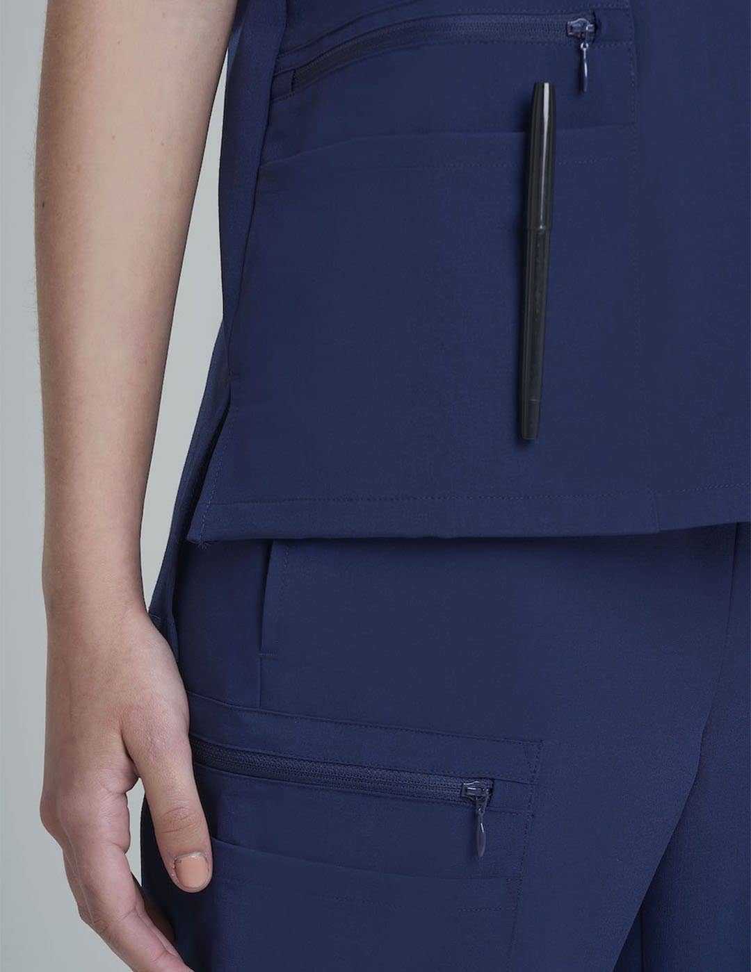 Durable royal blue V-neck scrub top for women, crafted with six pockets for everyday use. Model is wearing size X-Small