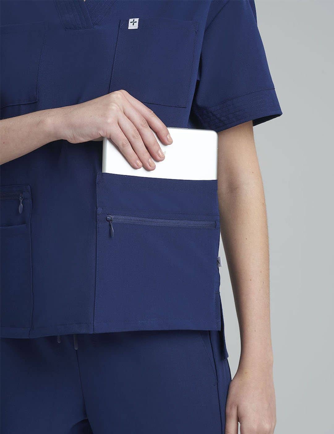 Royal blue women's scrub top with eight pockets, designed for functionality and professional wear. Model is wearing size X-Small