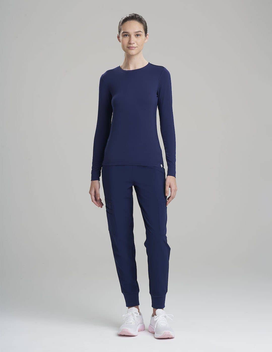 Women's Luxe long sleeve underscrub shirt in navy, offering premium comfort for professional layering. Model is wearing size X-Small